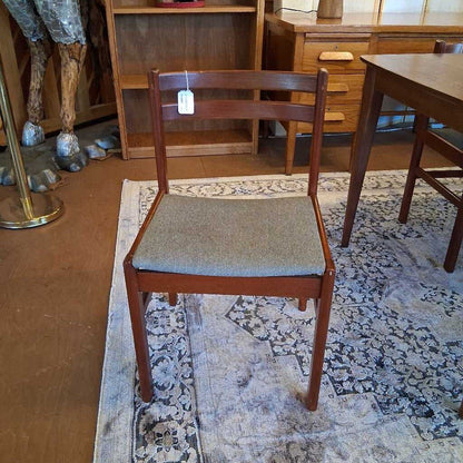 Wooden chair with a gray cushion on a patterned rug in a room with furniture.