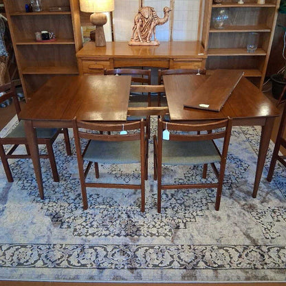 Wooden dining table with chairs in a room with shelves and decor.