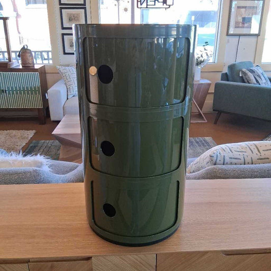 Green cylindrical container on a wooden surface in a living room