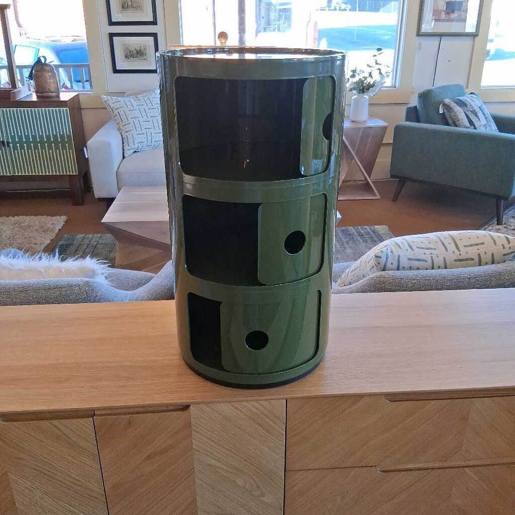 Green cylindrical storage unit on a wooden coffee table in a living room.