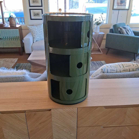 Green cylindrical storage unit on a wooden coffee table in a living room.