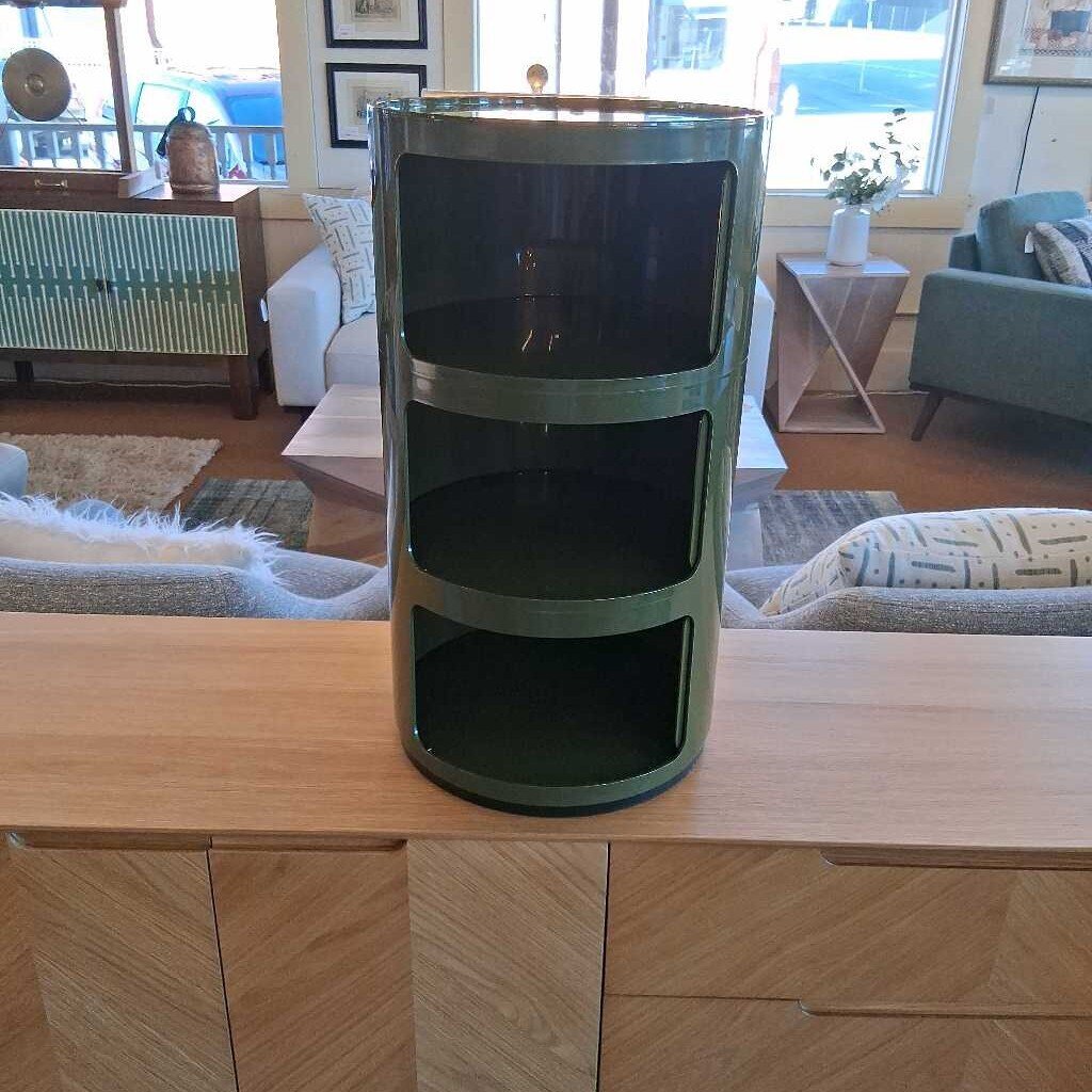 Green cylindrical storage unit on a wooden surface in a living room setting