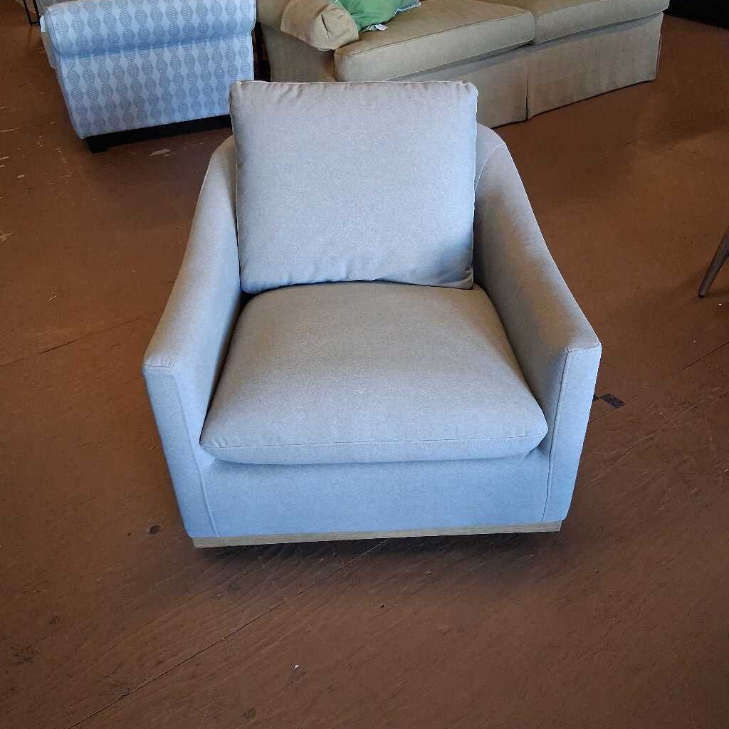 Light gray armchair with a pillow on a wooden floor