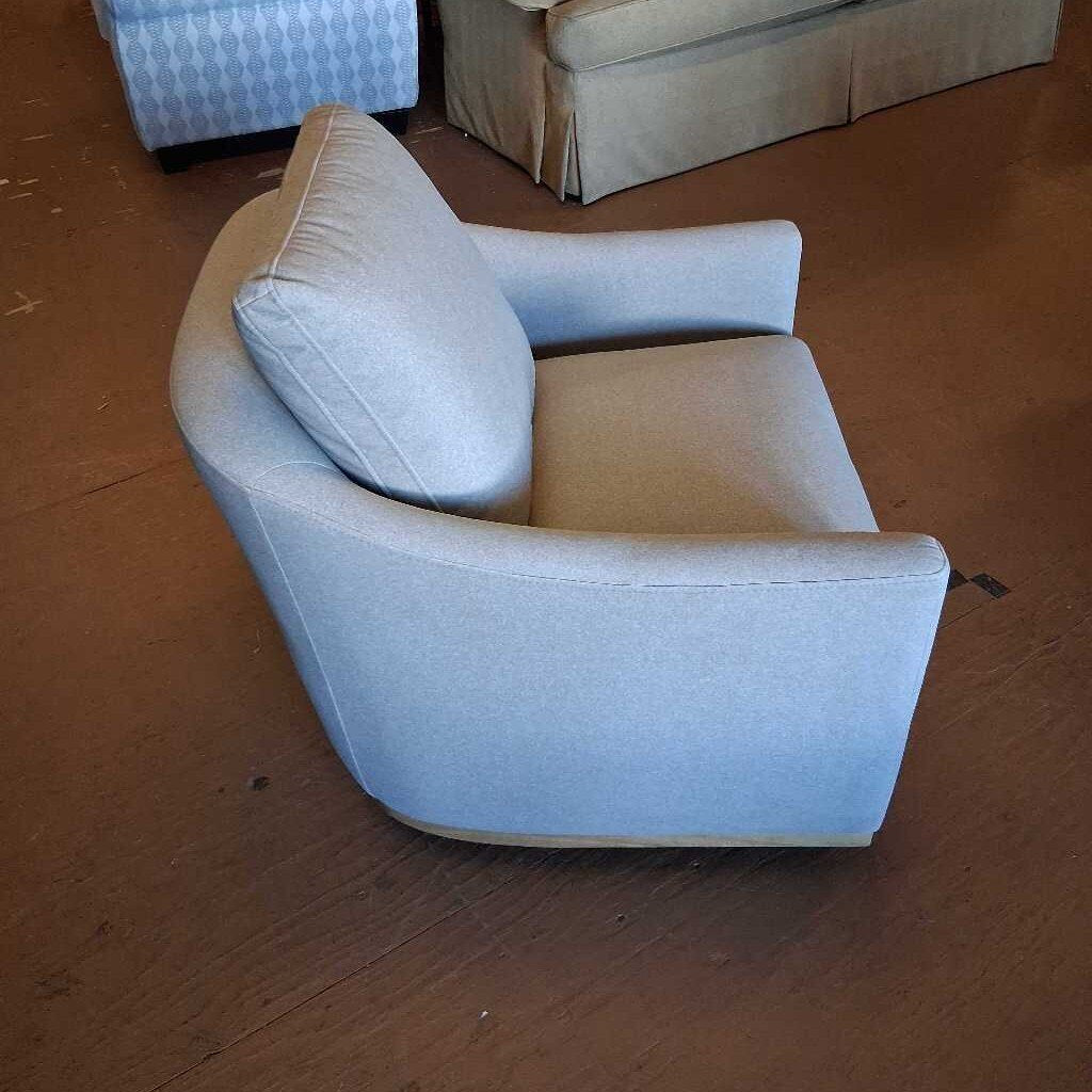 Light blue armchair on a wooden floor with a beige sofa in the background.