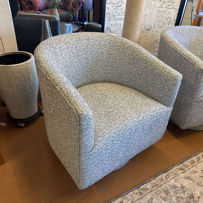 Two gray textured armchairs in a room with a patterned rug and decorative items.