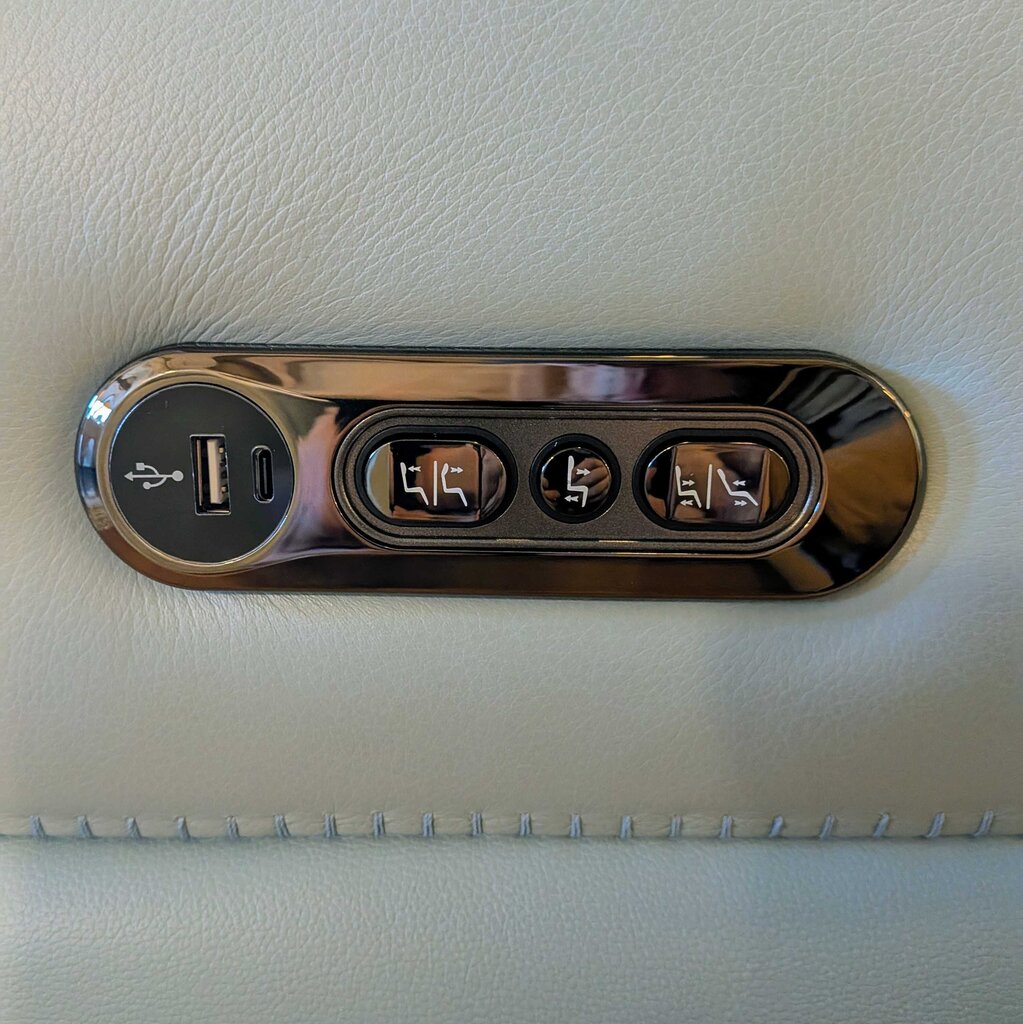 Car console with USB port and multiple outlets on a beige leather surface