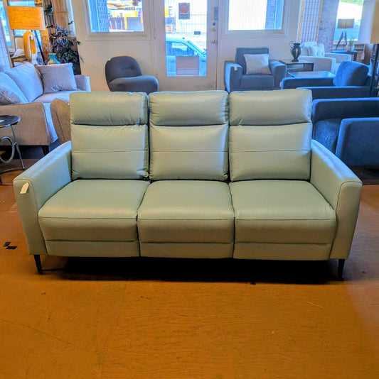 Light green sofa in a showroom setting with other furniture.