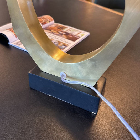 Decorative lamp with a gold U-shaped design on a dark surface