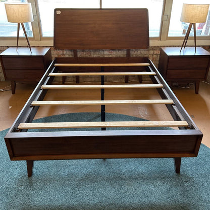 Wooden bed frame with wooden headboard and footboard in a room setting.
