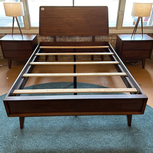 Wooden bed frame with wooden headboard and footboard in a room setting.