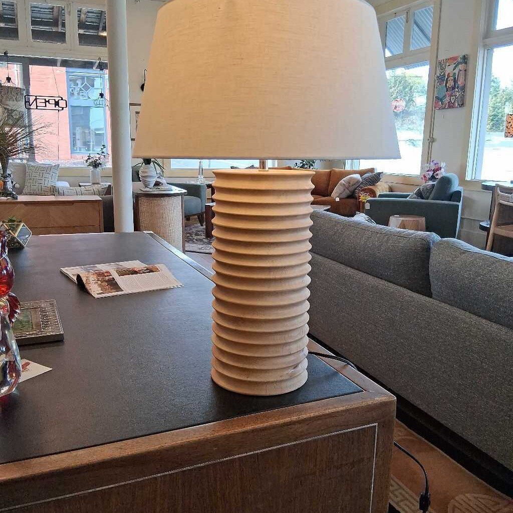 Decorative lamp with ribbed design on a wooden table in a living room.