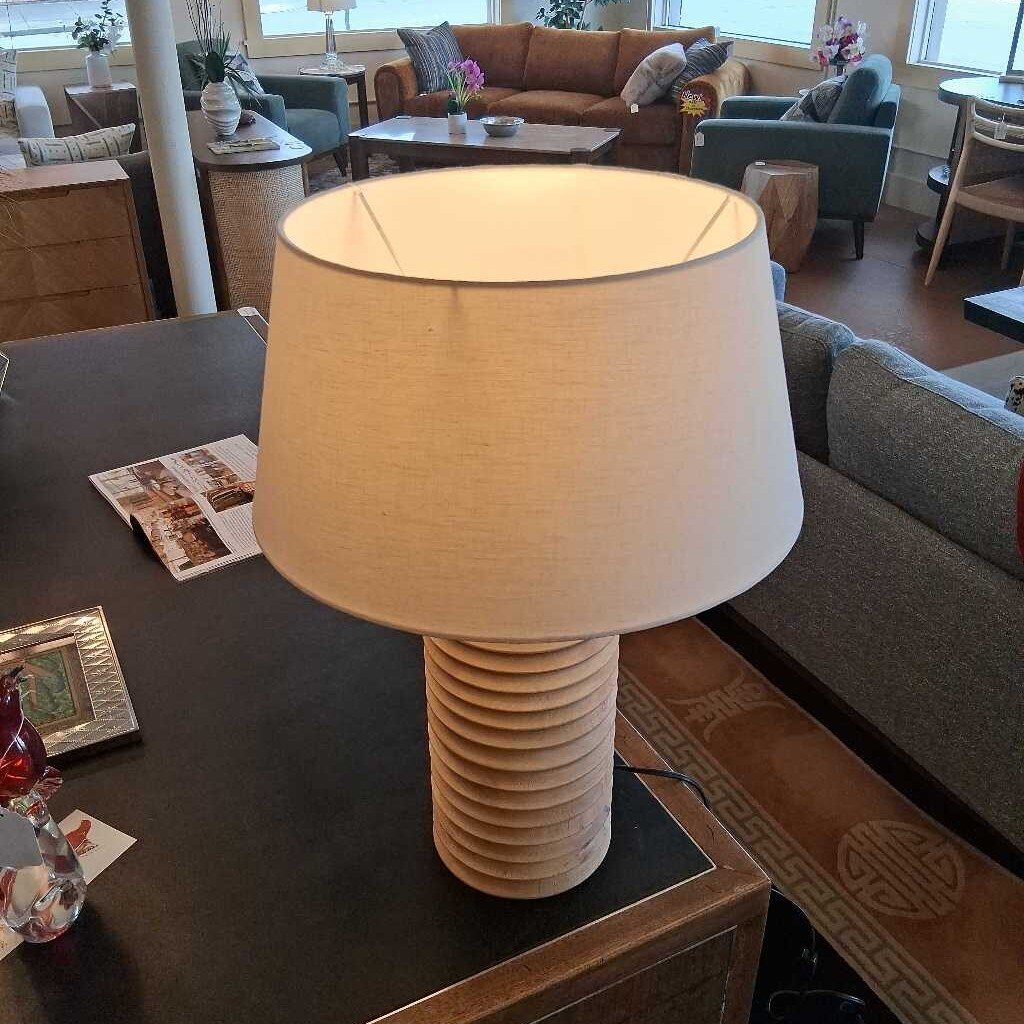 Beige table lamp on a wooden side table in a living room setting