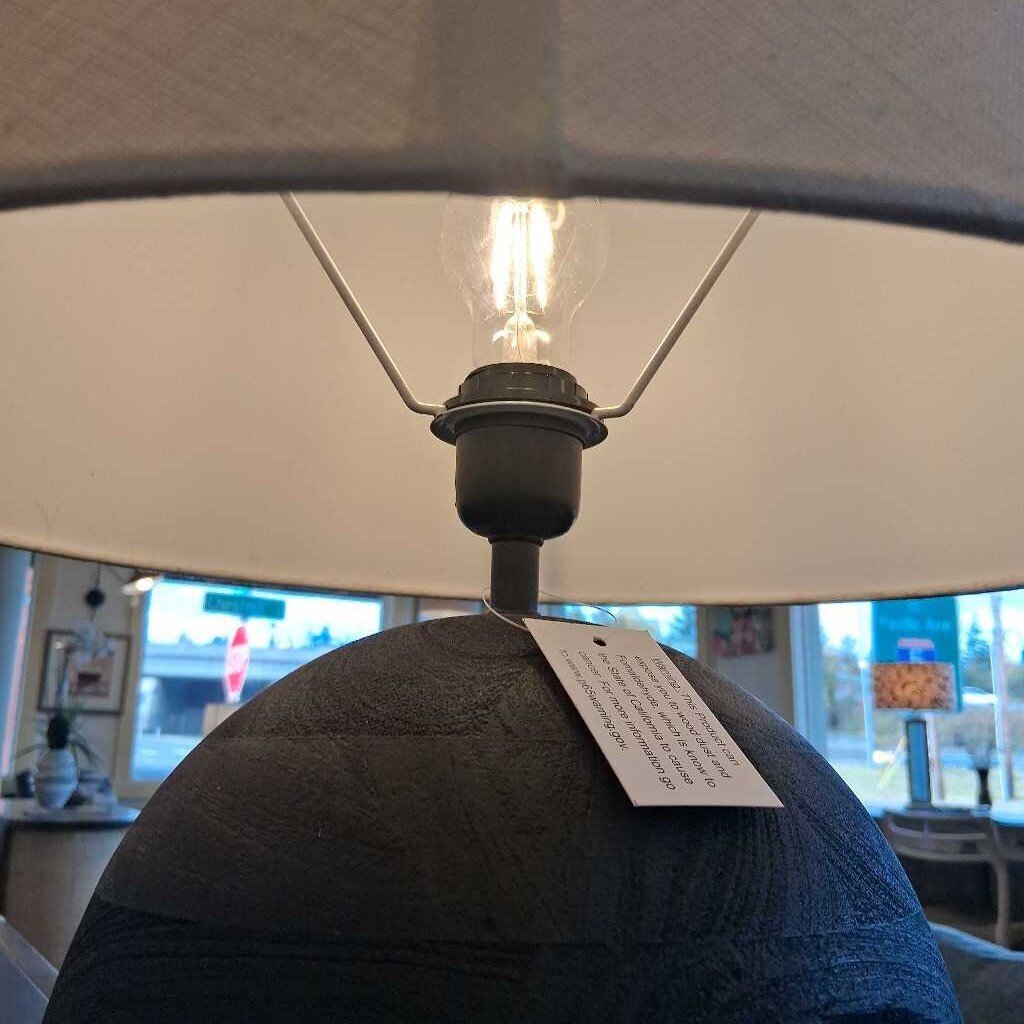 Close-up of a lamp with a visible light bulb and tag, blurred background