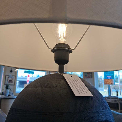 Close-up of a lamp with a visible light bulb and tag, blurred background