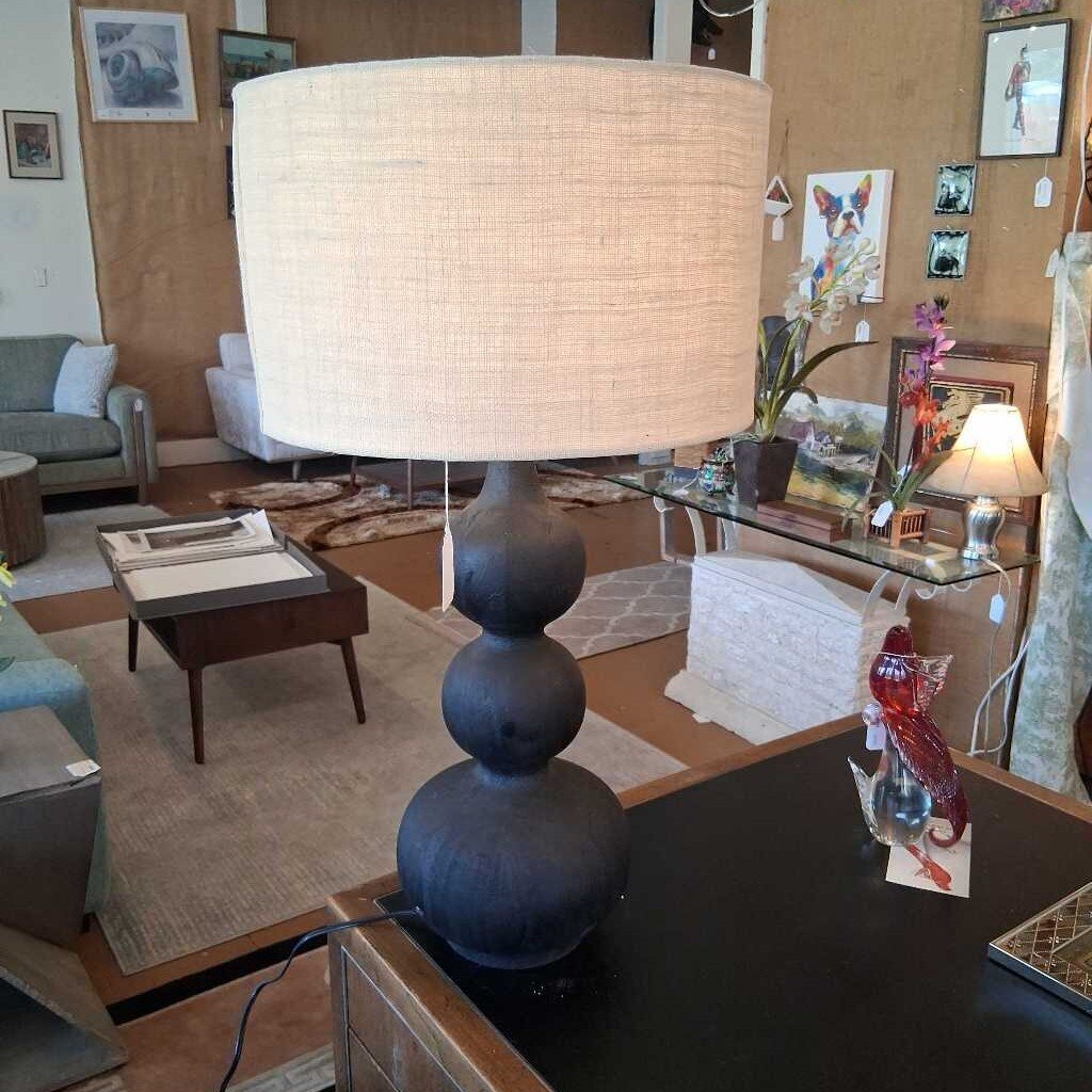 Lamp with a large white shade on a wooden table in a living room setting.