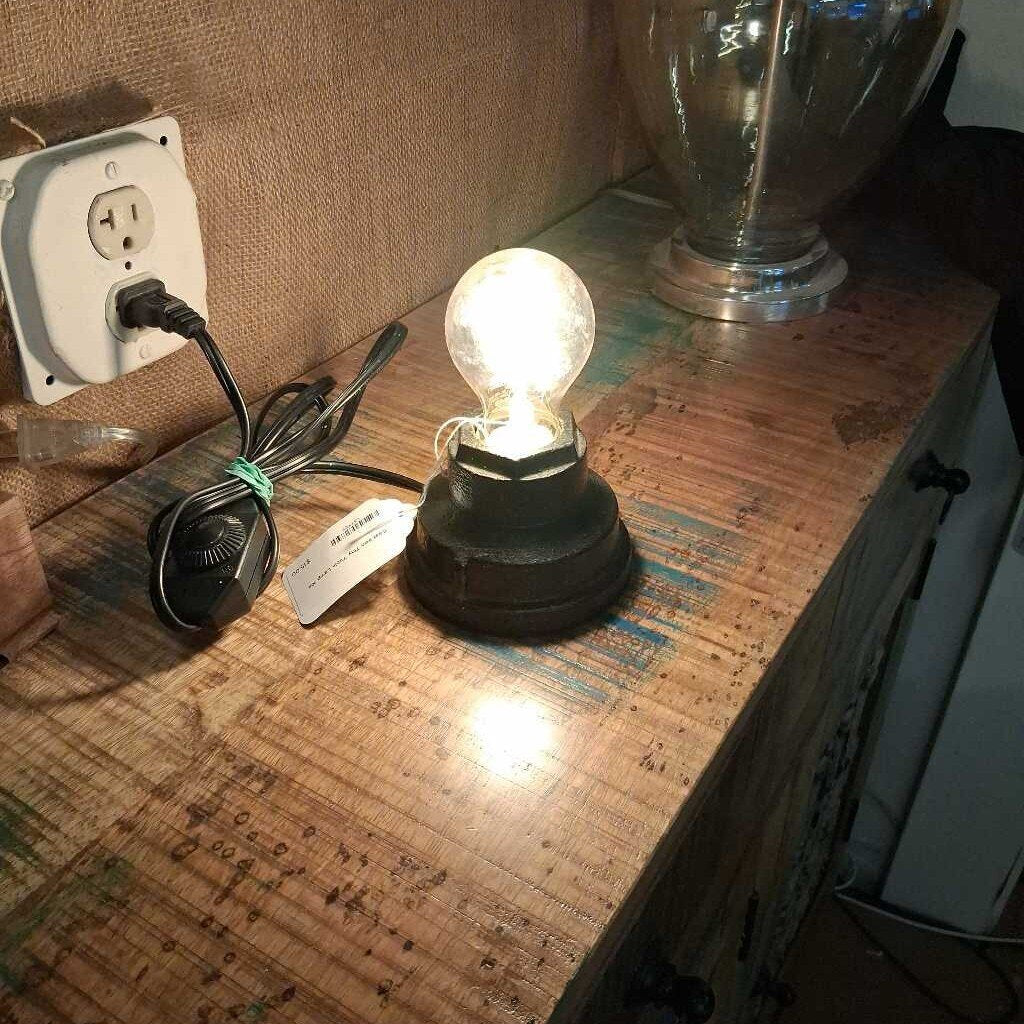 Vintage-style light bulb on a wooden surface with an electrical outlet in the background.