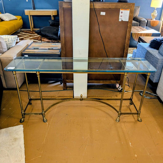 Glass table with gold metal legs in a storage or warehouse setting