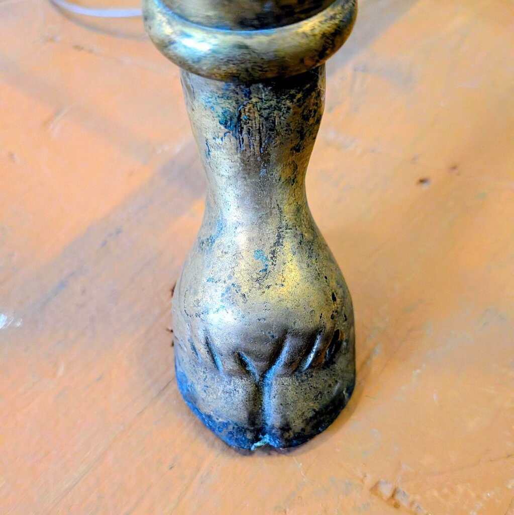 Bronze candle holder with paw print design on a wooden surface