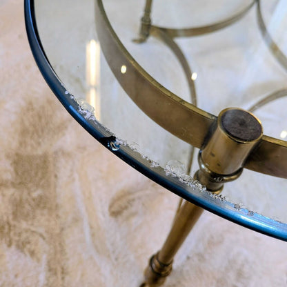 Glass table with brass base on a textured surface
