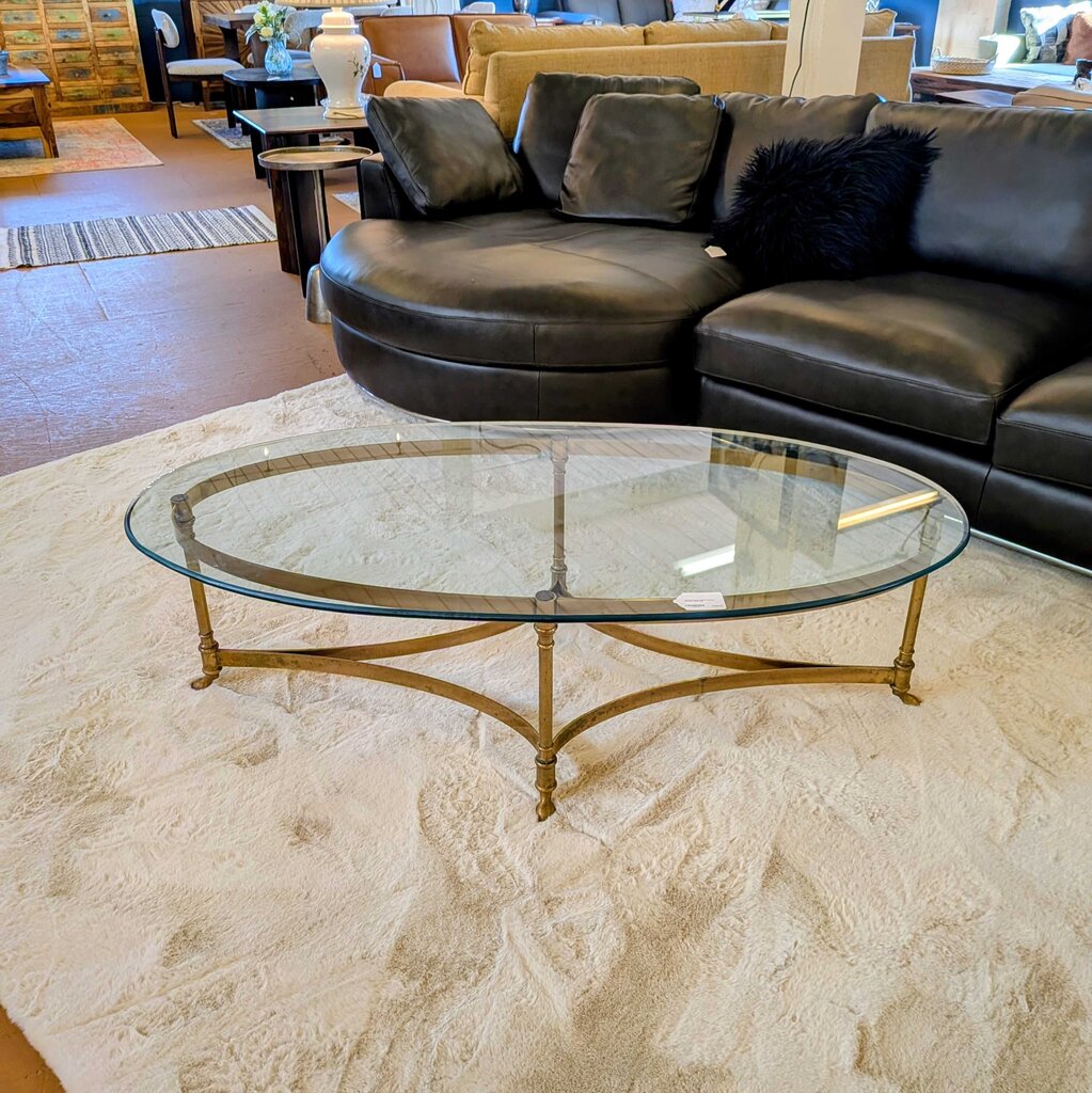 Black leather sectional sofa with a glass coffee table in a living room setting.