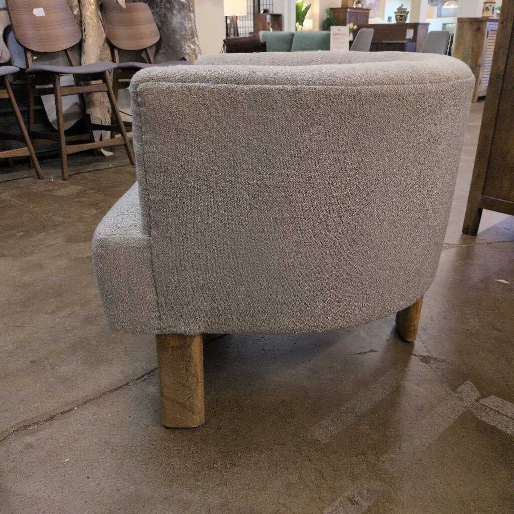 Gray upholstered chair with wooden legs in a furniture store setting