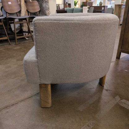 Gray upholstered chair with wooden legs in a furniture store setting