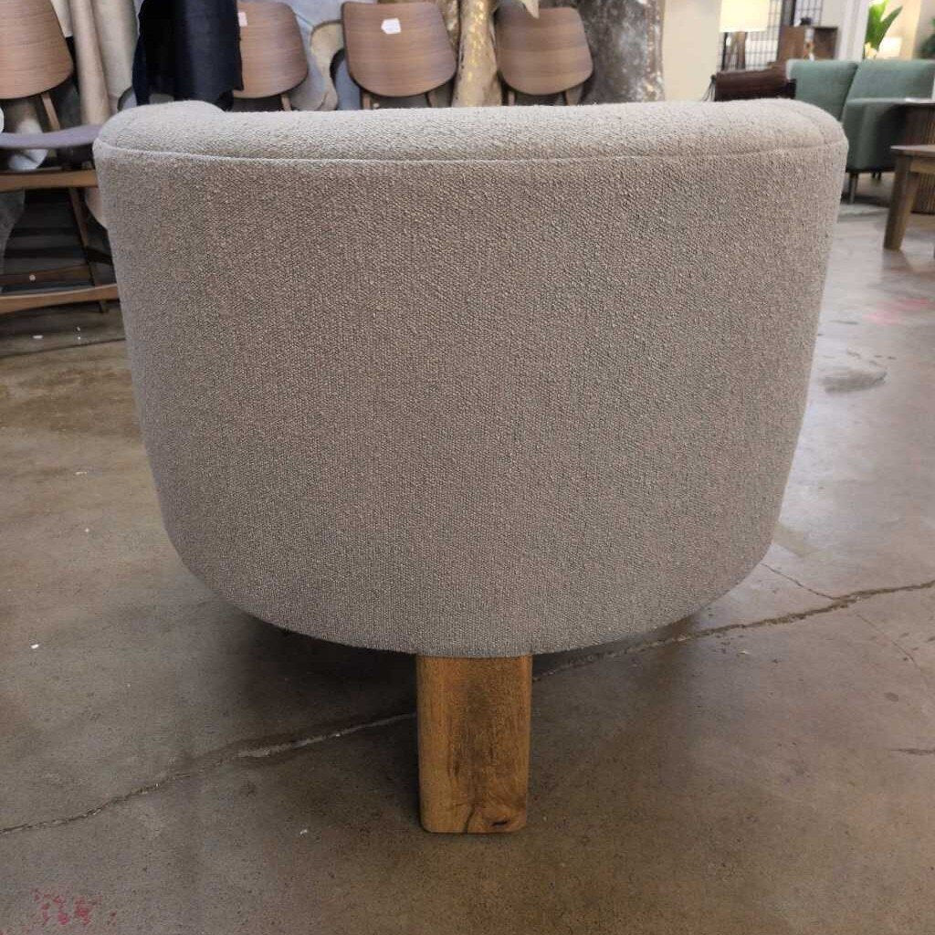 Gray upholstered chair with wooden leg in a showroom setting