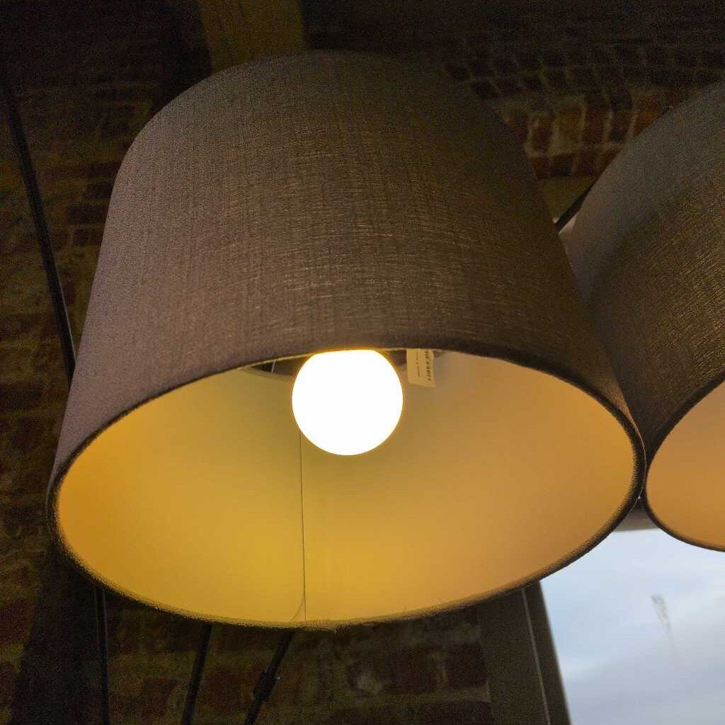 Lamp with a brown shade and visible light bulb inside, on a textured surface.