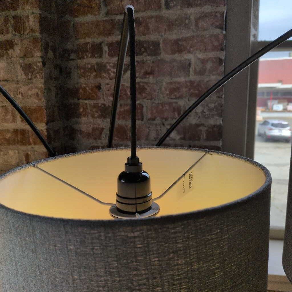 Close-up of a lampshade with a visible bulb socket against a brick wall.