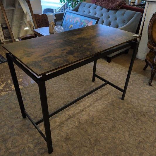 Wooden desk with metal legs in a room with a couch and table in the background