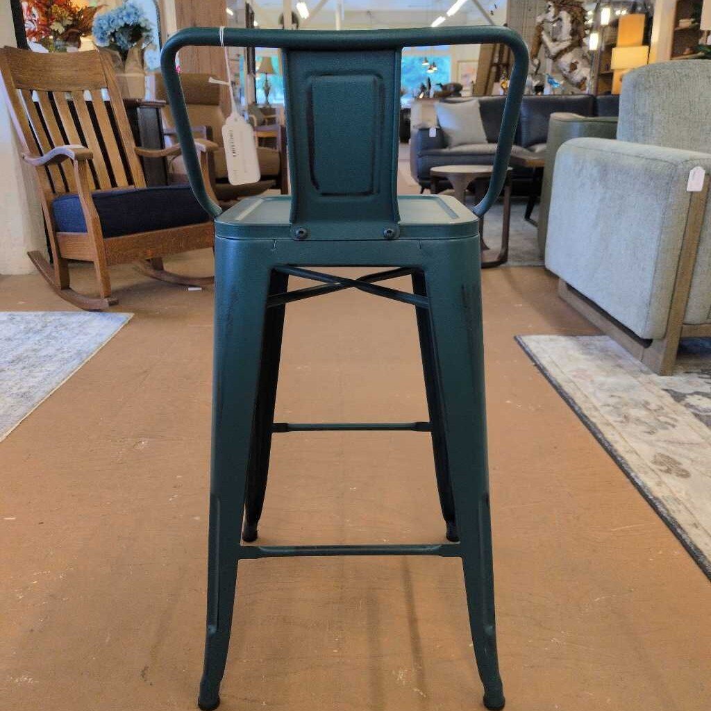 Green metal bar stool in a furniture store setting