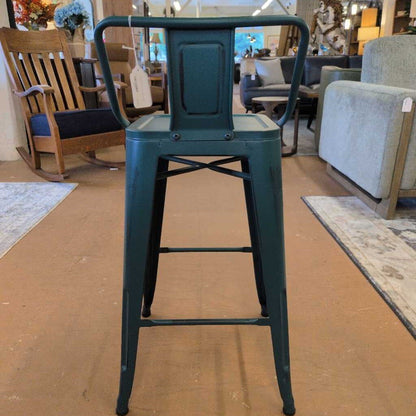Green metal bar stool in a furniture store setting