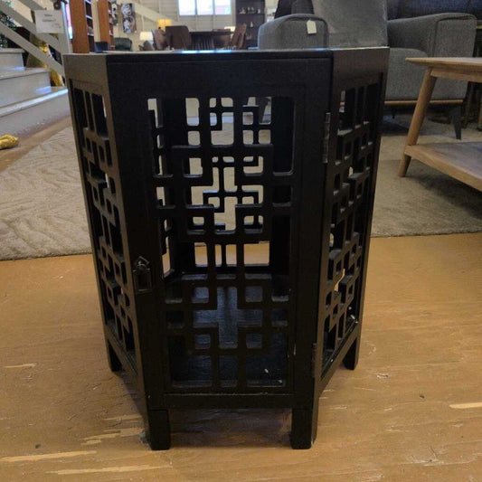Black lattice-patterned side table in a room setting