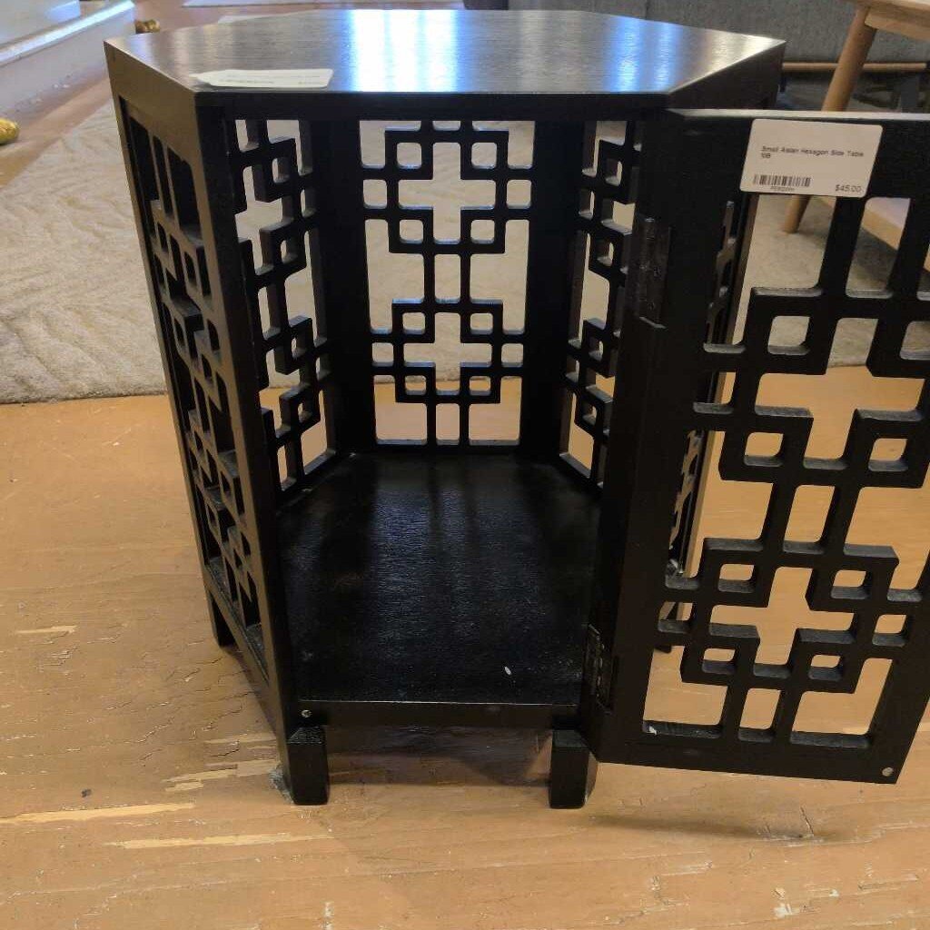 Black metal decorative shelf with lattice design on a wooden floor.