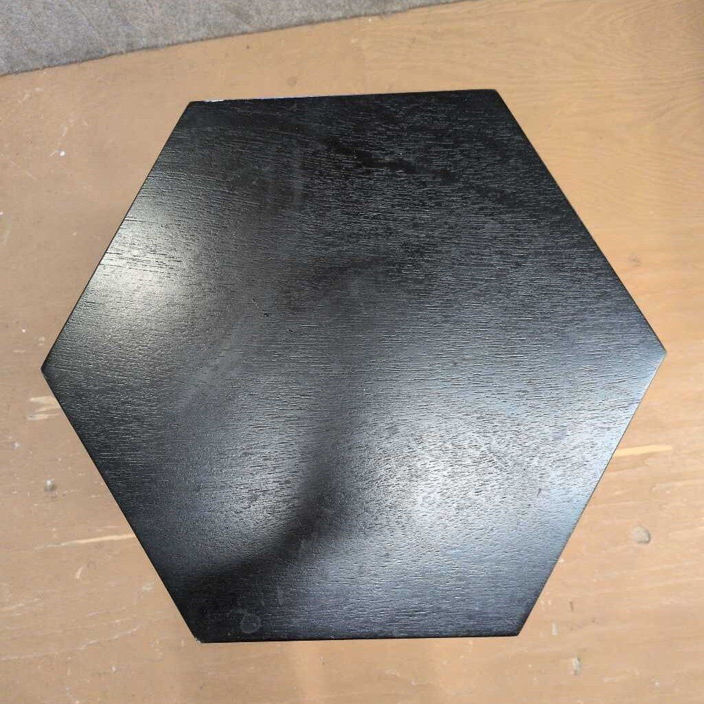 Hexagonal black metal block on a wooden surface