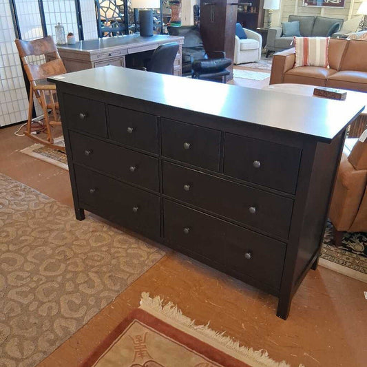 Dark wooden dresser in a living room setting with furniture and decor.