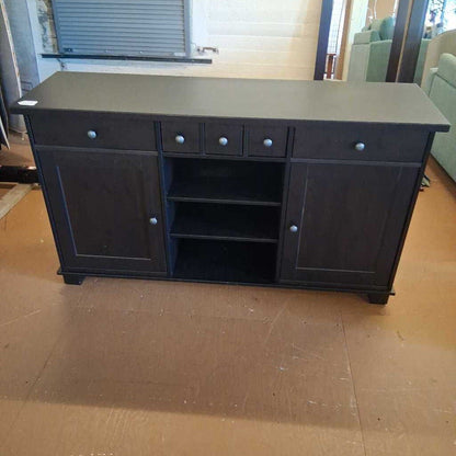 Dark wooden sideboard with multiple drawers and doors on a wooden floor.