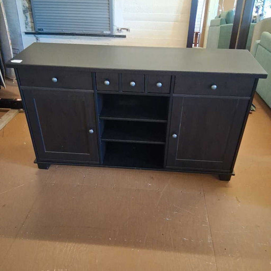 Dark wooden sideboard with multiple drawers and doors on a wooden floor.