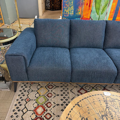 Blue sofa in a room with a colorful painting and patterned rug.