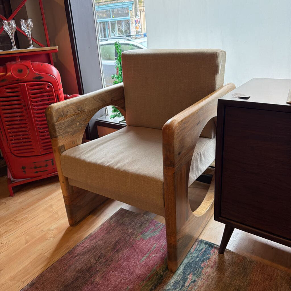 Wooden armchair with beige cushion in a room with a red heater and window.