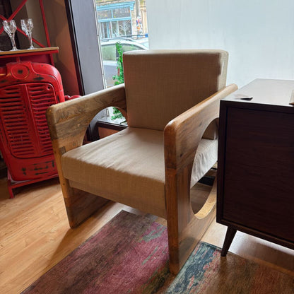 Wooden armchair with beige cushion in a room with a red heater and window.