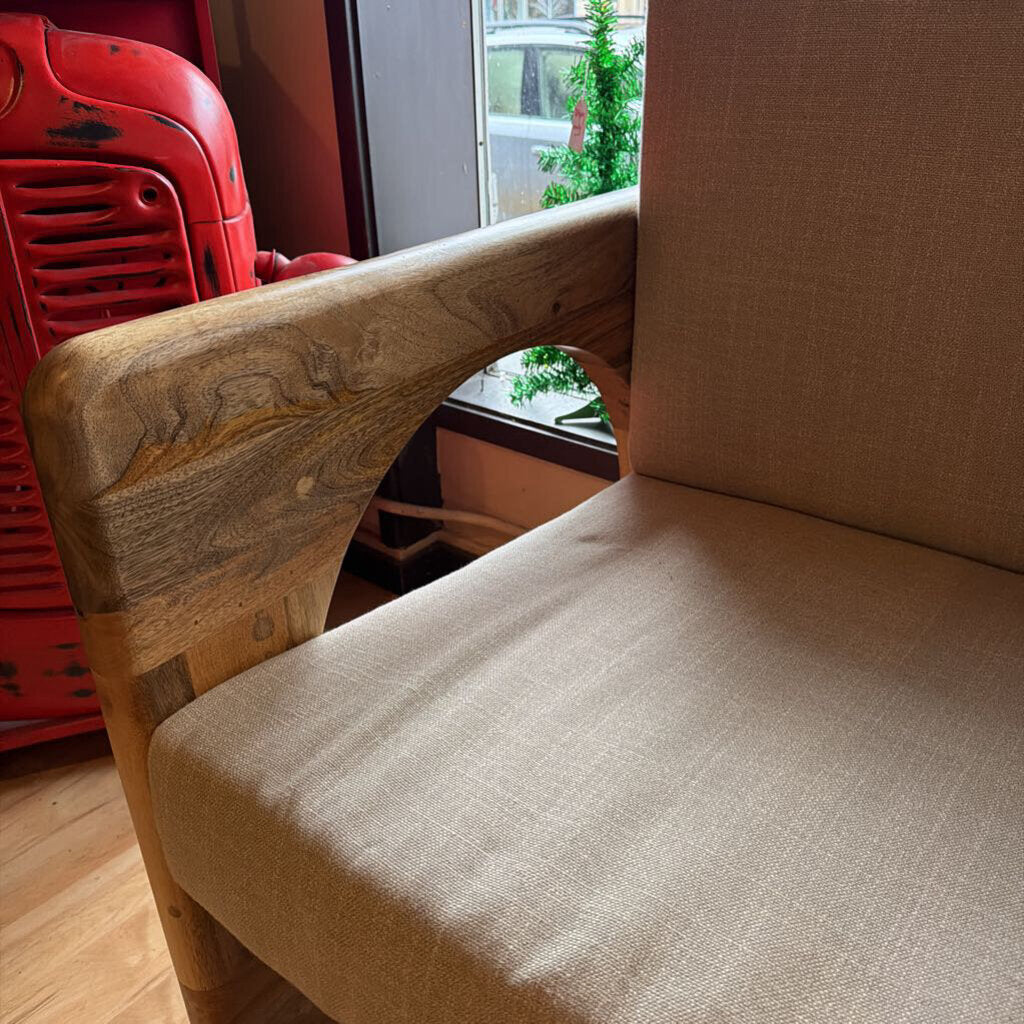 Chair with wooden backrest and beige cushion in a room with a red vehicle and window in the background.