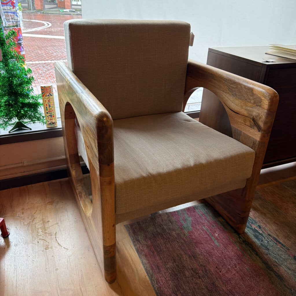 Beige armchair with wooden arms in a room with a window and rug.