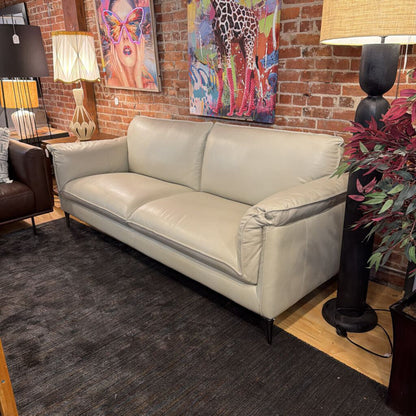 Beige sofa in a room with colorful artwork on the wall.