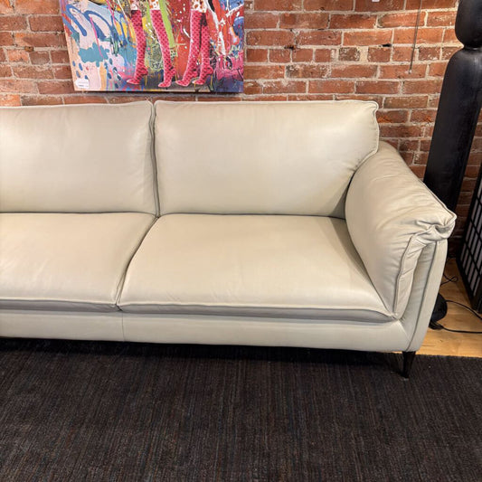 Beige sofa in a room with a brick wall and colorful abstract painting.