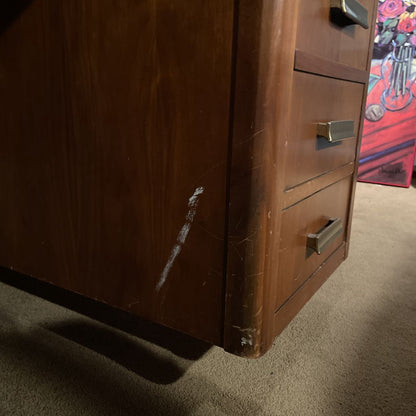 Wooden dresser with visible wear and tear on a carpeted floor