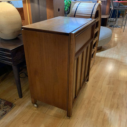 Wooden folding table on wheels in a room with wooden flooring.