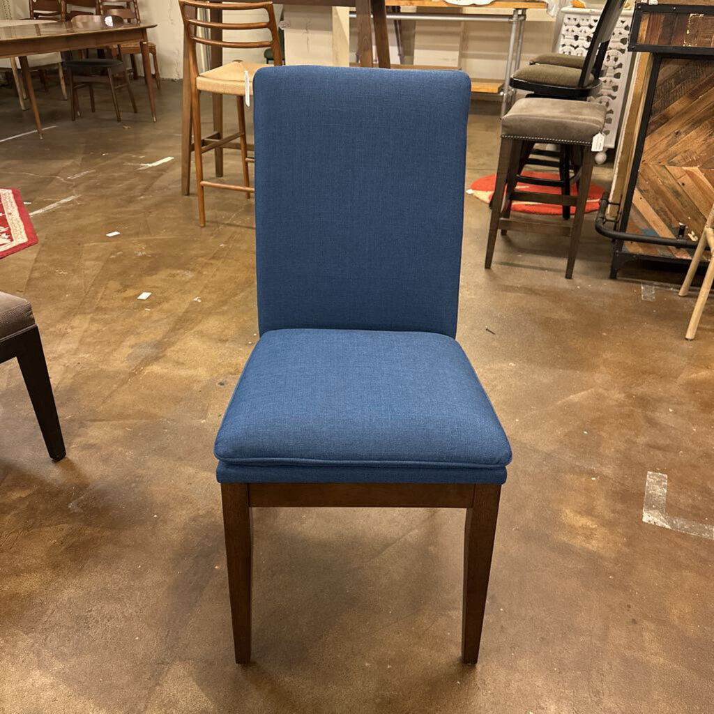 Blue chair with wooden legs on a brown floor