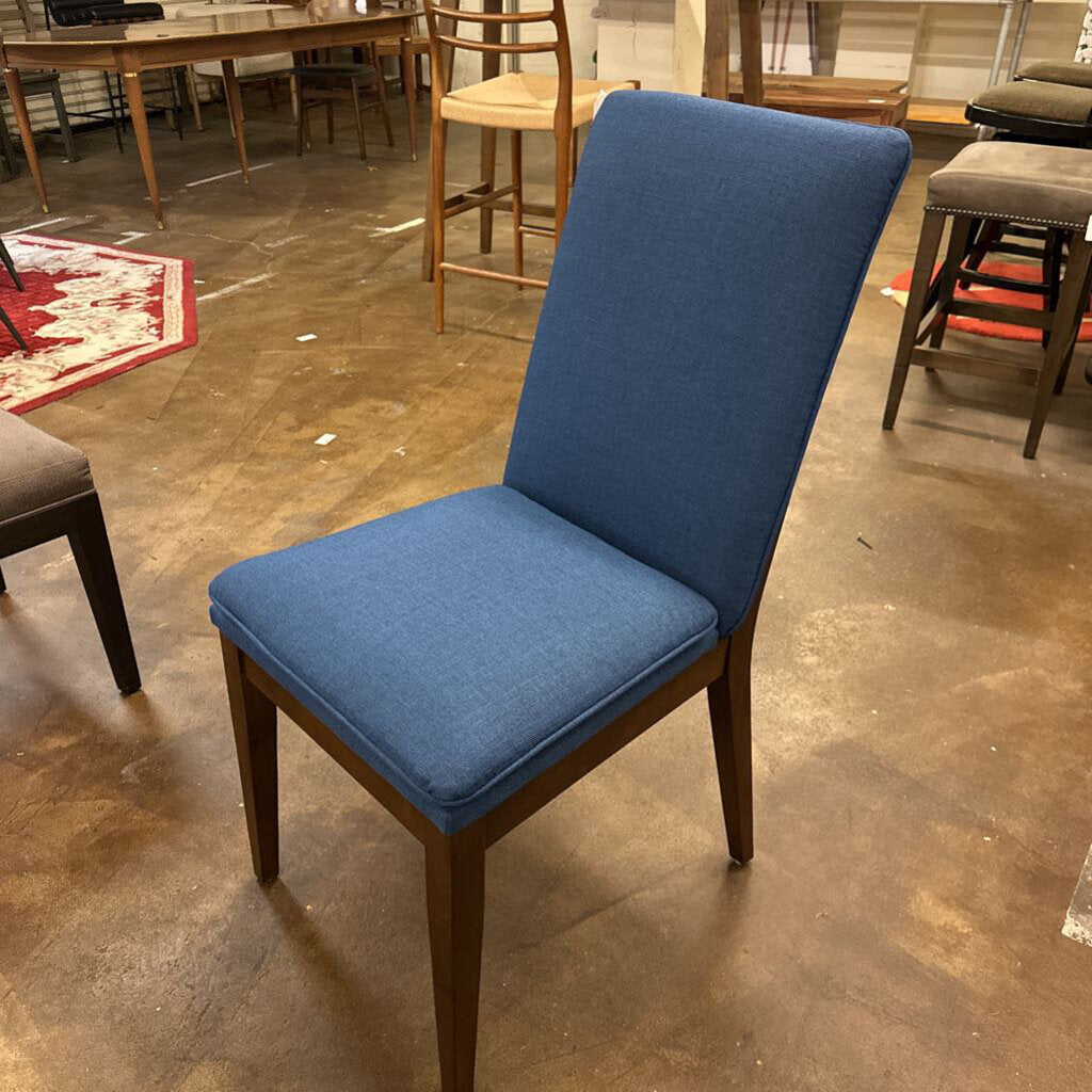 Blue chair with wooden legs on a concrete floor