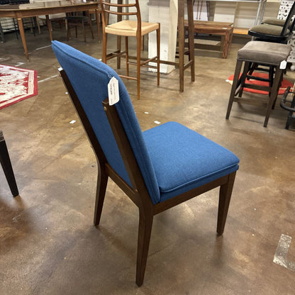 Blue chair with wooden frame on a concrete floor in a warehouse setting